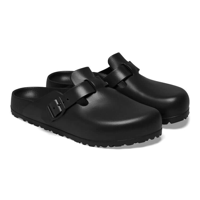 Black slip-on clogs with adjustable buckle strap, featuring a sleek and modern design for comfort and style.
