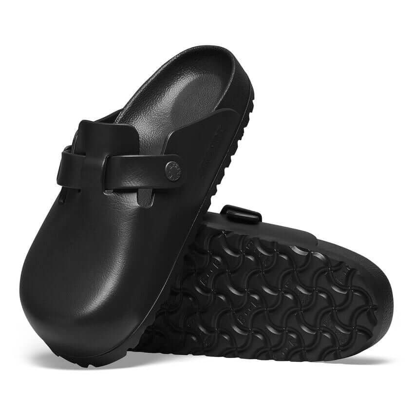 Black slip-on clogs with textured soles and buckle detail