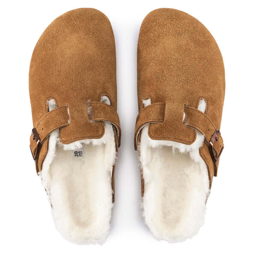 Brown suede slip-on clogs with white plush lining and adjustable straps