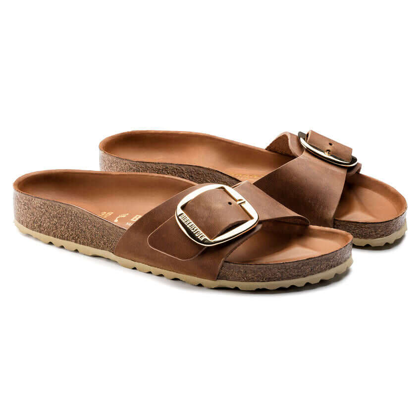 Brown leather slide sandals with buckle and cork sole.