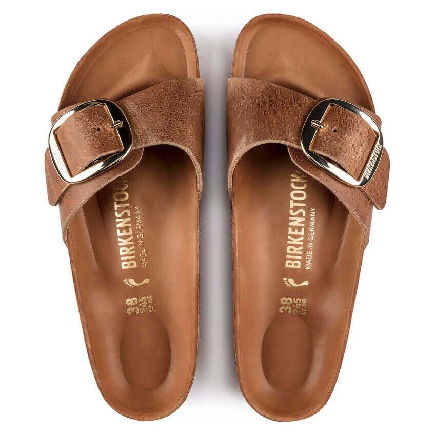 Brown Birkenstock sandals with gold buckle detail, top view