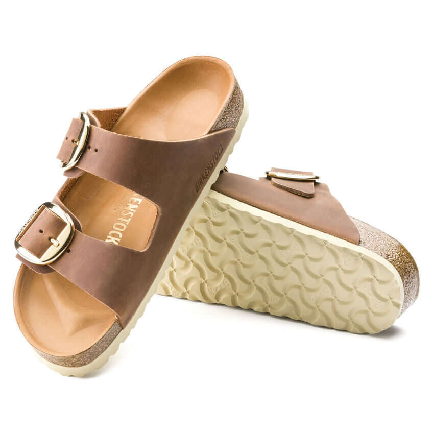 Brown leather sandals with double straps and buckle detailing, featuring a soft, textured sole for added comfort and support.