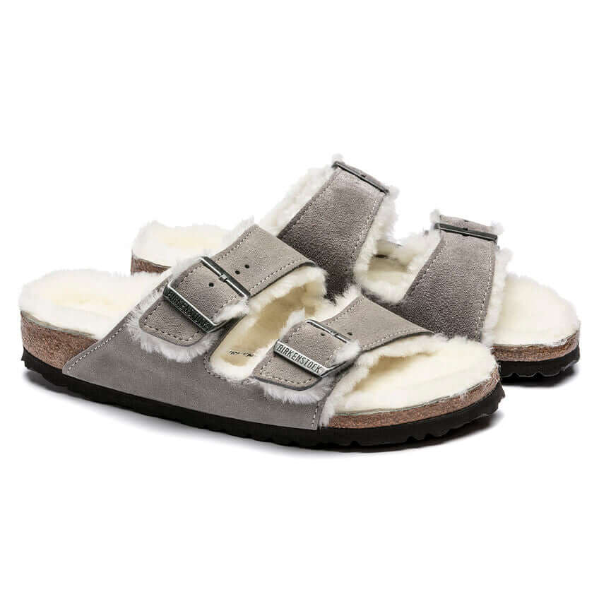 Grey suede shearling-lined sandals with double buckle straps on cork soles.