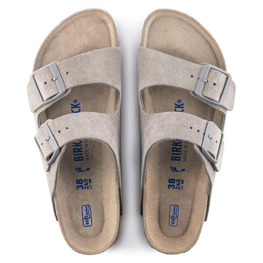 Top view of beige Birkenstock Arizona sandals with double adjustable straps and blue logo on footbed.